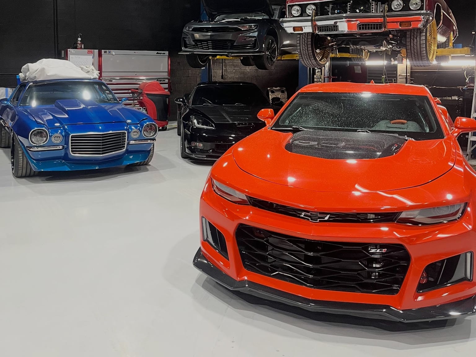 An orange sixth-generation Camaro ZL1 and a blue second-generation Camaro on the Custom Speed Creations shop floor
